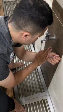 A Muslim man performing ablution and washing arms.
