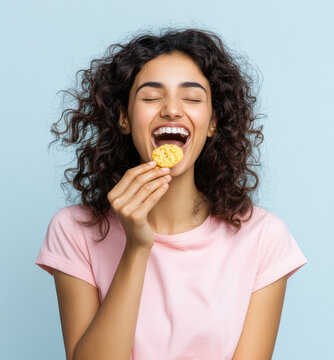young indian girl eating cookie on white background