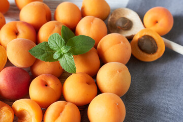 Fresh ripe apricots with mint on wooden table, closeup