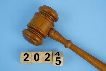 Wooden gavel and flipping numbers 2024 and 2025 on wooden cubes. Concept of new laws in year 2025.	