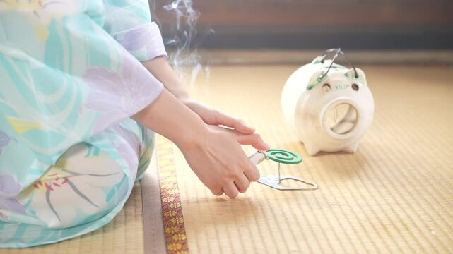 京都の古民家で浴衣を着た女性が蚊取り線香に火をつけている