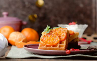 Sweet Belgian waffles with caramelized orange on a pink purple plate.  