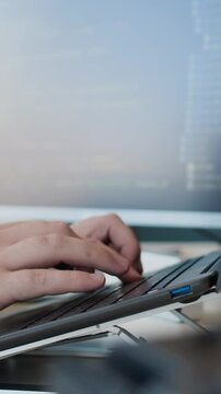 Medium closeup of unrecognizable male programmers hands typing code on laptop in office