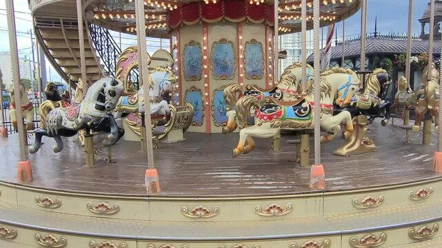 Carousel with beautiful horses is spinning. City attraction against the backdrop of beautiful house. Horizontal video 4k.