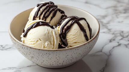 Three scoops of vanilla ice cream topped with chocolate sauce in a bowl on a marble background.