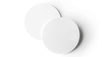 Two blank white round paper coasters on a white background. Mockup and product display concept.