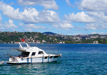 Luxury yacht cruising on the Bosphorus with Istanbul\'s lush hillside in the background under a clear summer sky