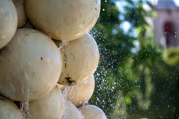 Water cascading over large spherical sculptures in a lush garden setting during daylight