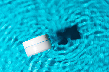 Sunscreen bottle floating in a clear blue swimming pool on a sunny day