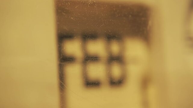 A mechanical flip clock changing a month name behind an old plastic case