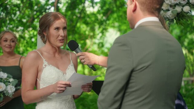 Bride reads vows to groom, looks up and smiles, while maid of honor wipes tears