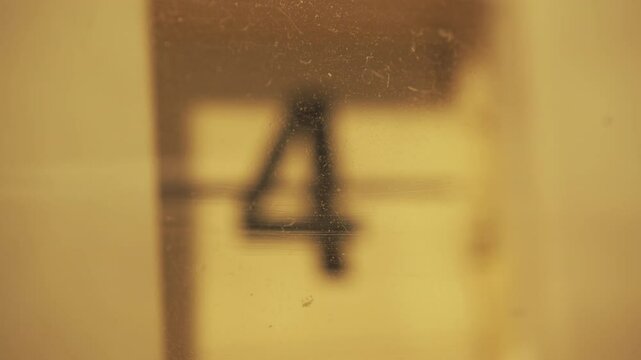 A flip clock changing date number behind an old plastic case