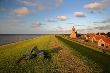 The dike alongside the sea shore (Wadden Sea) at sunset in the terp village Wierum, Friesland,...