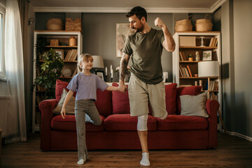 Teaching fitness. Father and his little daughter are at home together doing workout and having fun