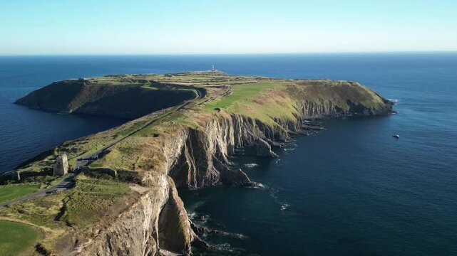 Dramatic cliffs, calm blue ocean Old Head headlands with golf course and light house in county Cork, near Kinsale, Ireland
