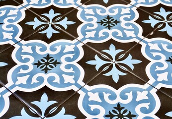Blue, white, and dark gray ceramic floor tile with decorative pattern texture isolated on horizontal ratio background.