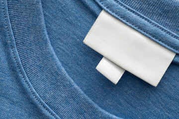 Blank white laundry care clothes label on blue shirt fabric texture background