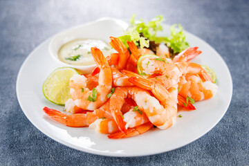 Fresh shrimp with sauce and lemon slice on a plate, perfect for seafood lovers. Ideal for culinary presentations and restaurant menus