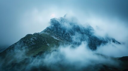 Fototapeta premium Mountaintop engulfed in dense foggy clouds