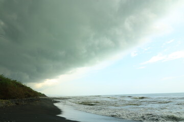 a beach with a black sand beach and a cloudy sky