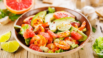 Holiday shrimp salad with avocado and grapefruit on a rustic wooden surface. Ideal for festive gatherings and healthy celebrations