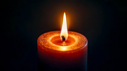 Single candle burning brightly in the darkness