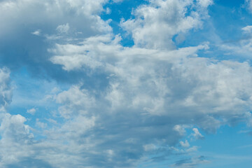 The image depicts a serene and expansive sky filled with a variety of fluffy, white clouds against a vibrant blue backdrop.