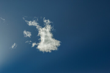 The image depicts a serene and expansive sky filled with a variety of fluffy, white clouds against...