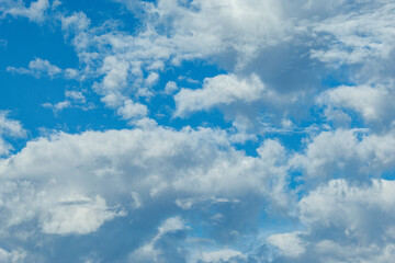 The image depicts a serene and expansive sky filled with a variety of fluffy, white clouds against a vibrant blue backdrop.