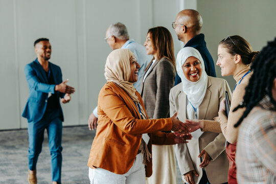 Diverse professionals exchanging handshakes and greetings at a lively business conference event