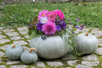 graue Kürbisse dekoriert mit Blumenkranz als Herbst-Dekoration