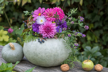 grauer Kürbis dekoriert mit Blumenkranz als Herbst-Dekoration