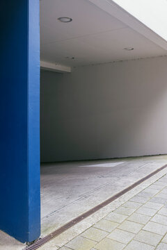 A partially visible blue wall within a corridor of an urban setting, a simple and minimalistic design highlighting the modern architecture and functional space use.