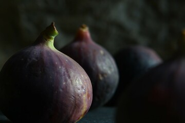 Purple figs on a black stone plate. Photo, background with fresh, juicy, ripe tropical fruits. Suitable for depicting vegetarian and raw, healthy food, harvest. Symbol of abundance and enlightenment.