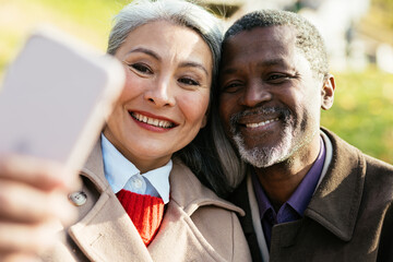 Storytelling image of a multiethnic senior couple in love. Man and woman with warm clothes spending time outdoor.