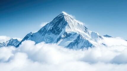Snowy mountain peak rising above the clouds, space for copy in the crisp blue sky.