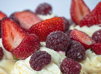 close up of strawberry and raspberry tart with a white frosting
