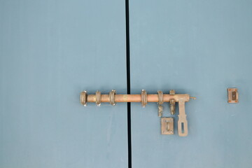 Metal old retro long shape door lock or latch on painted blue gray wood door.