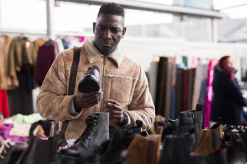 Man looks at used shoes at a flea market
