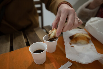 Pastry being dipped into espresso coffee