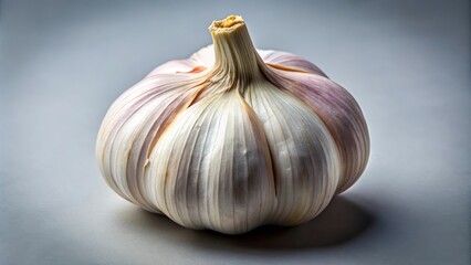Single garlic bulb is sitting on a gray background, with its papery skin and cloves visible