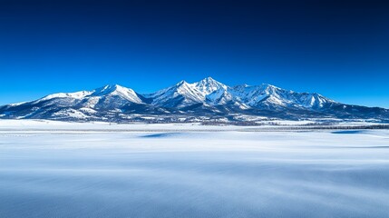 Obraz premium A serene winter landscape featuring snow-covered mountains under a clear blue sky.