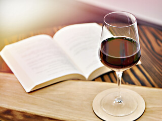 Vintage glass of red wine and book