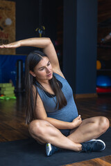 Pregnant woman in the gym doing warm-up. Sitting on a yoga mat.