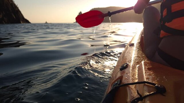 Kayaking Ocean Sunset California - A close-up view of a woman kayaking in the ocean with the sunset in the background. The photo was likely taken in California.