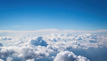 Fototapeta premium bright cloudy sky view from airplane. White clouds on blue sky background close up, cumulus clouds high in azure skies, beautiful aerial cloudscape view from above.
