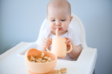 baby sitting in high chair, drinking clean water from baby sippy cup. weaning