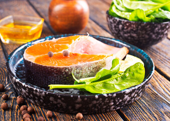 Fresh salmon fillets on dark wooden background with spices