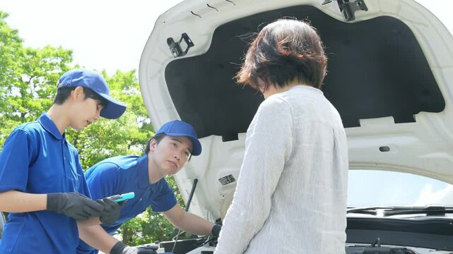 自動車のエンジンルームを点検する作業員