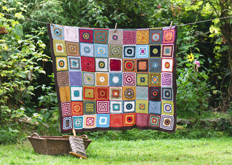 Vintage colorful blanket, make from crochet granny squares with different motifs, hangs on the...